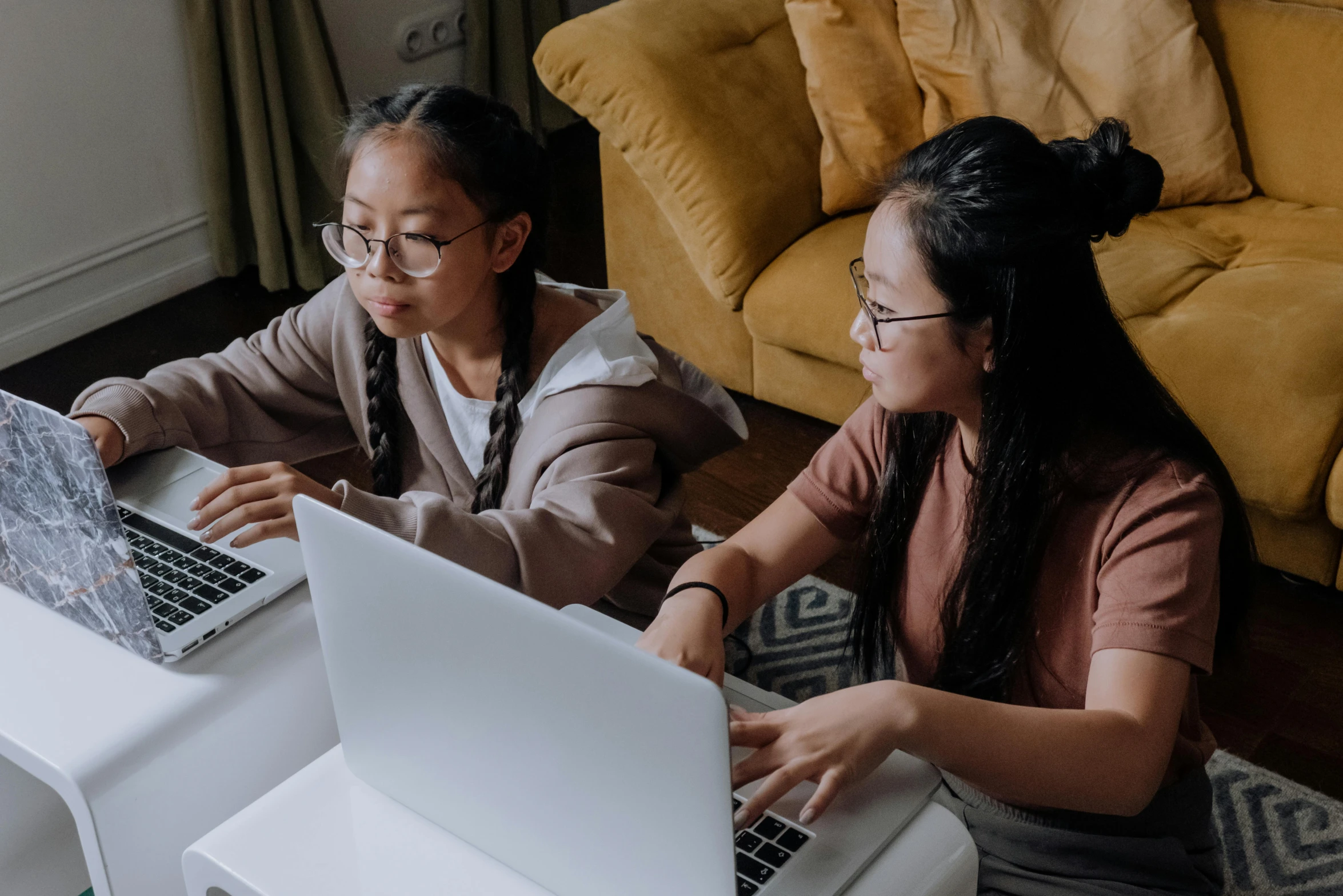 a couple of women sitting at a table with laptops