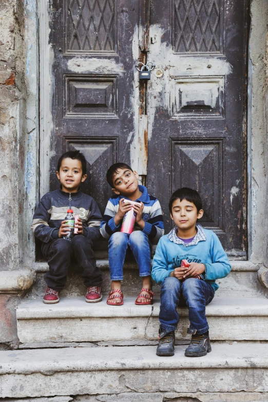 three boys and one girl are sitting on the steps