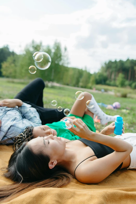 a couple of girls laying on top of a grass field