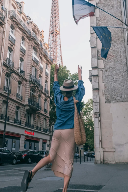 a woman dancing on the street in front of a very tall building