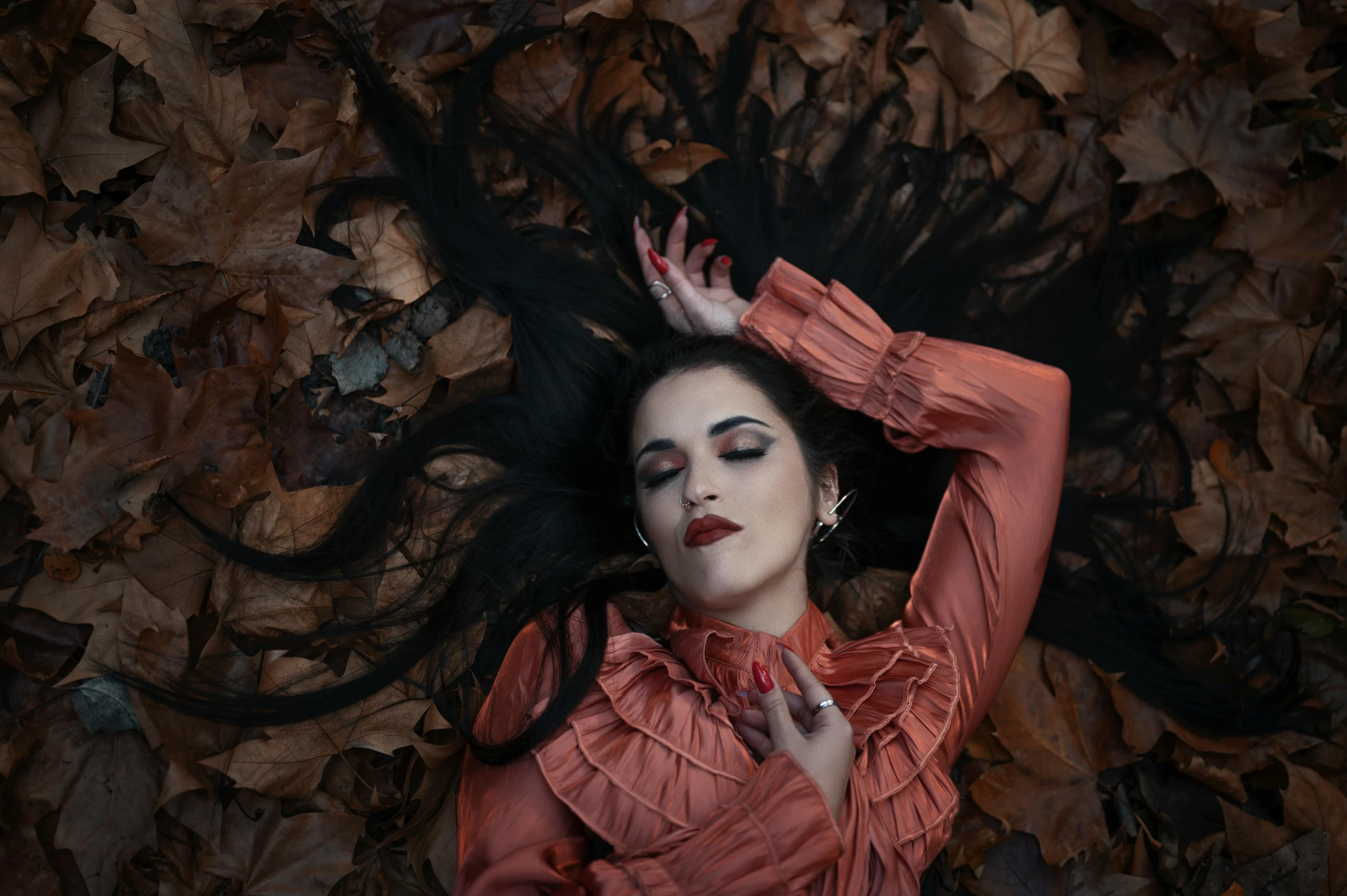 a woman with dark hair and makeup wearing an orange dress