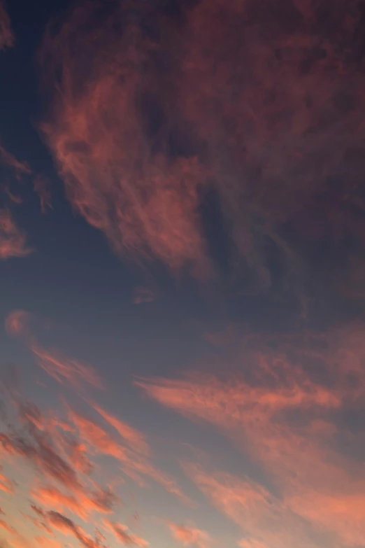 pink clouds glow in the sky above an orange sunset