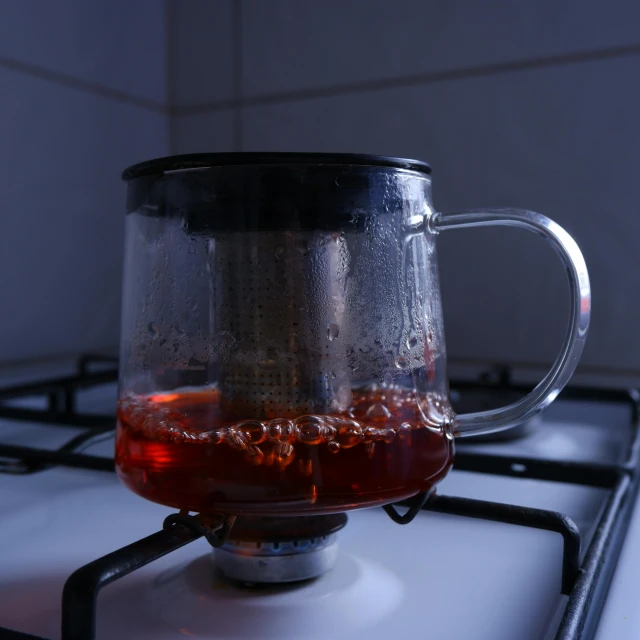 a glass mug filled with tea sits on a burner