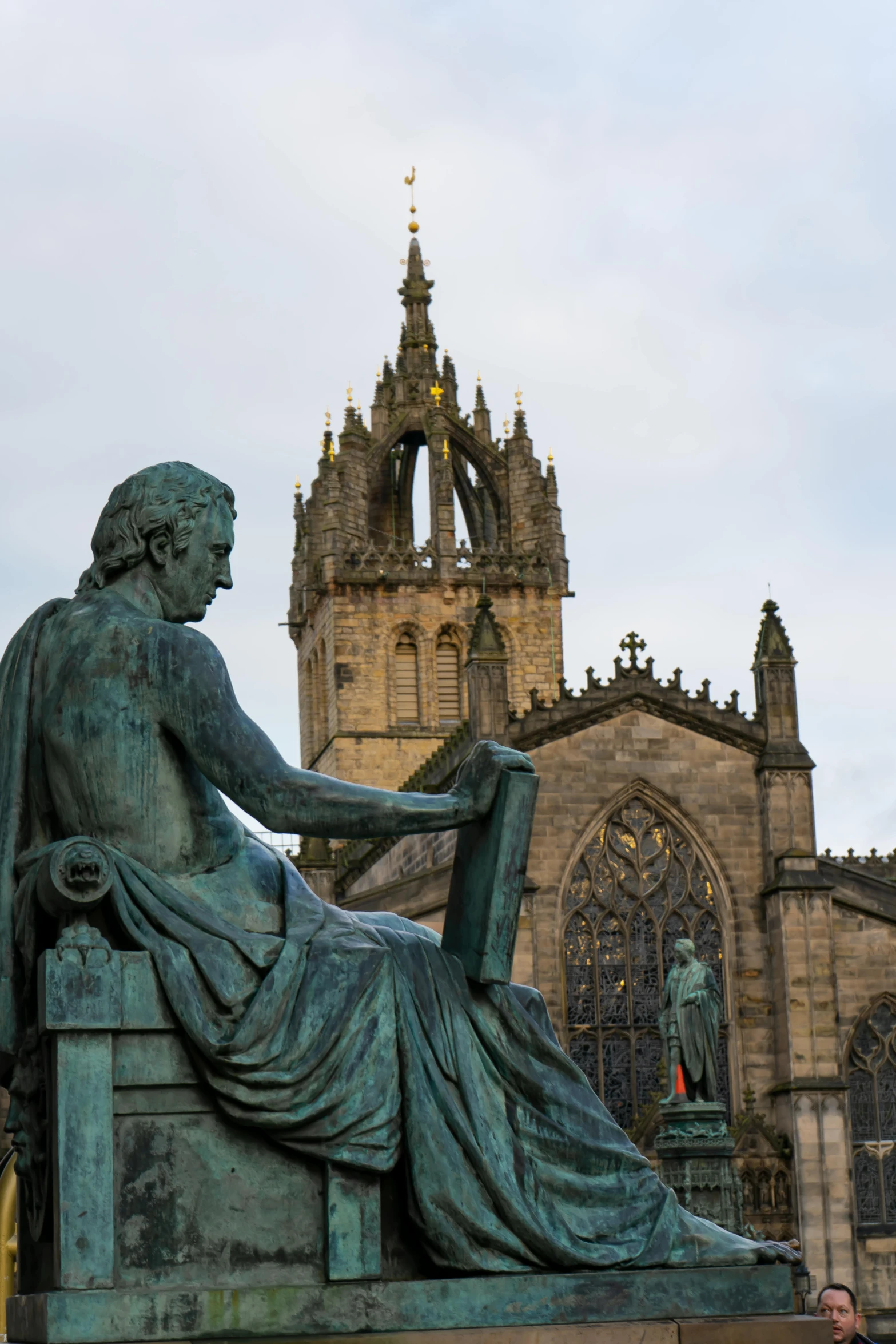 statue sitting in front of old building with gothic style architecture