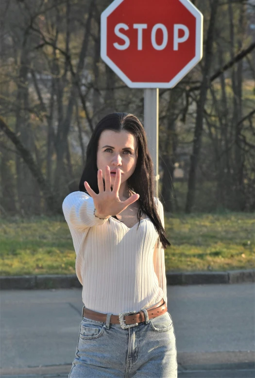 woman making an obscene hand gesture standing at a stop sign