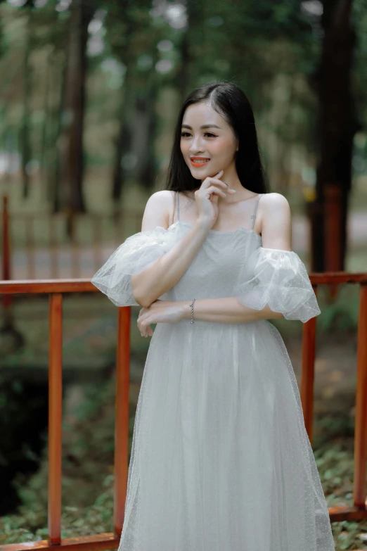 a woman poses in a white dress in the woods