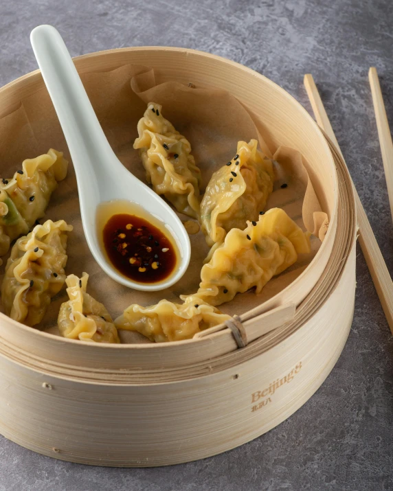 a spoon is shown resting on the asian dumplings in a wooden steamer