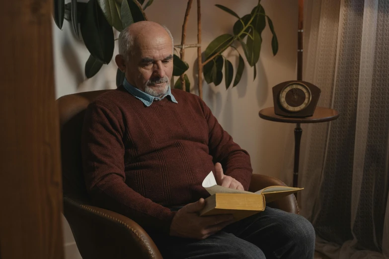 a man is reading in a chair with a book on it