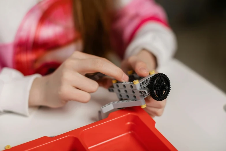 child working on a toy lego machine with his hands