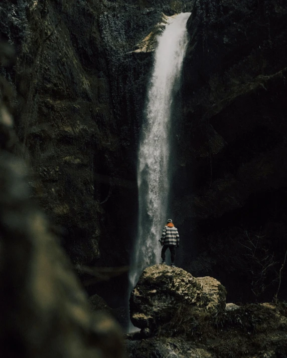a person standing in front of a large waterfall