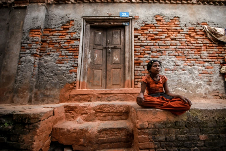 a woman sits on the steps outside of an old house