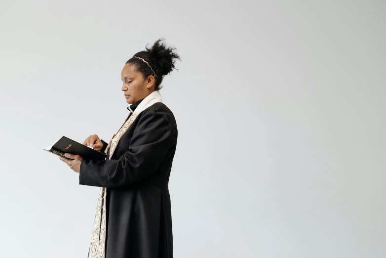 a woman wearing a black robe and holding a bible