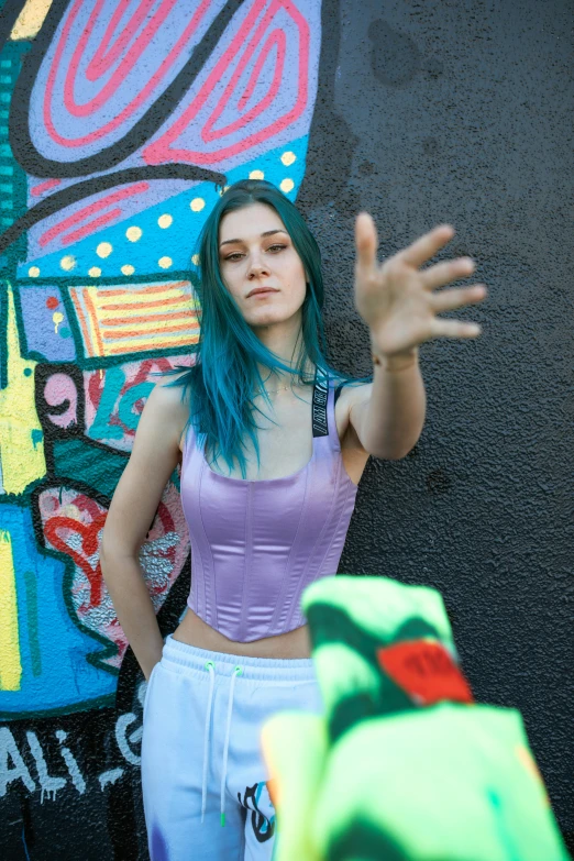 a woman with blue hair standing next to a wall