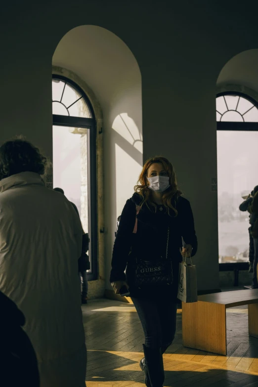 a woman is walking through an open building with a mouth mask on