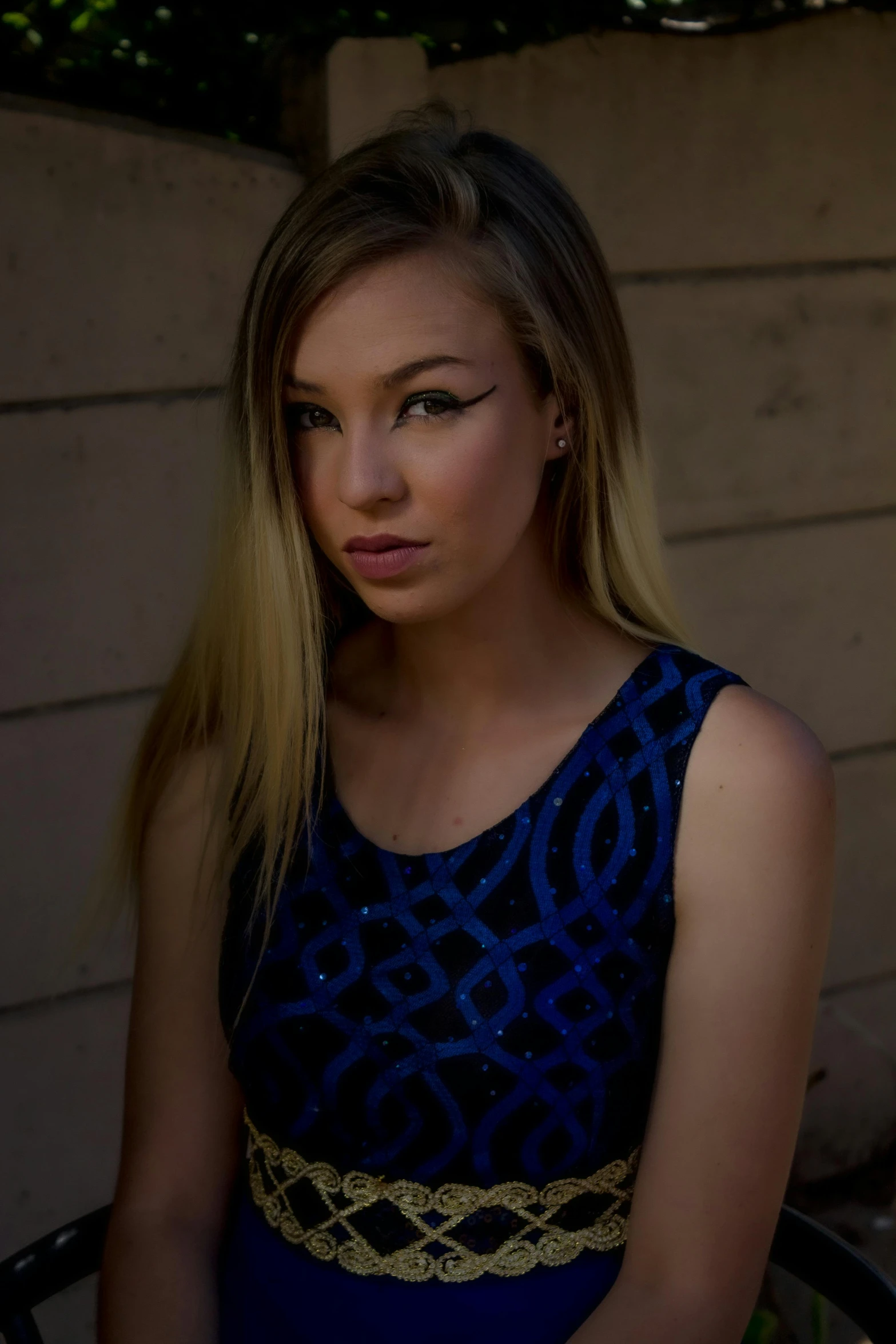 a woman in blue dress standing near wall