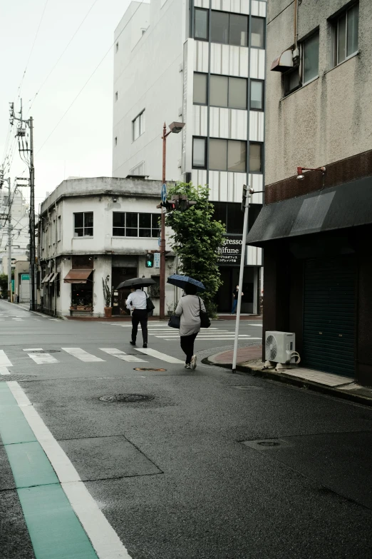 a man carrying an umbrella across a street