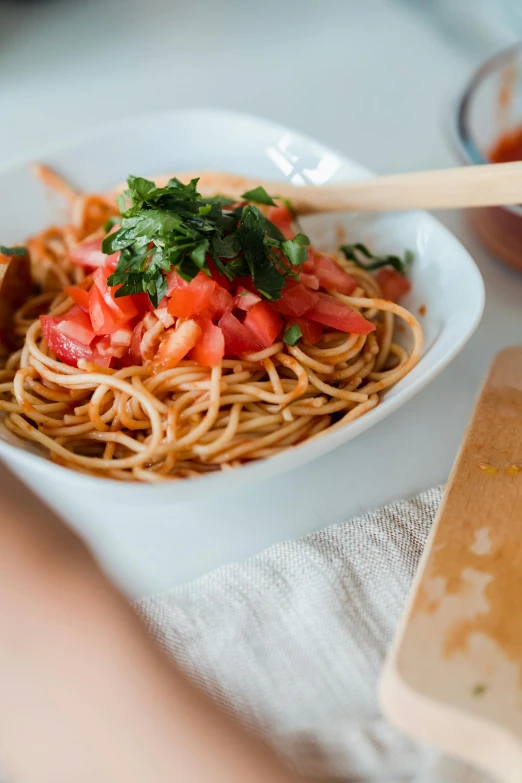 a plate of spaghetti with tomatoes and parsley