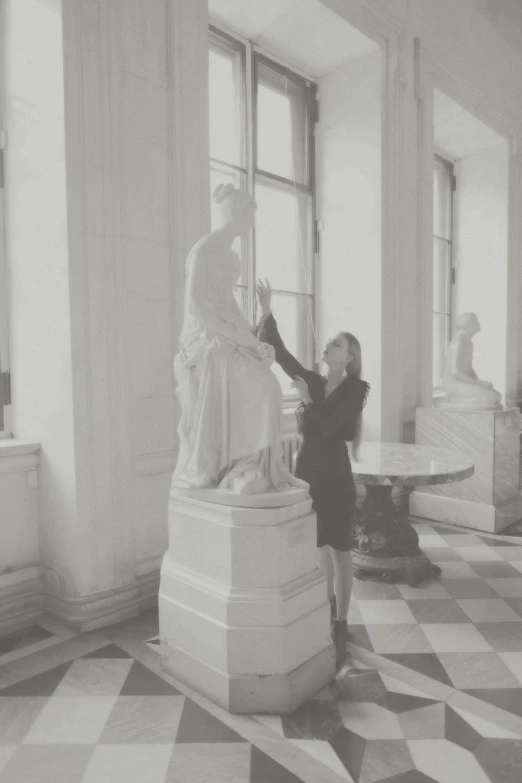 woman stands near a statue in an empty building