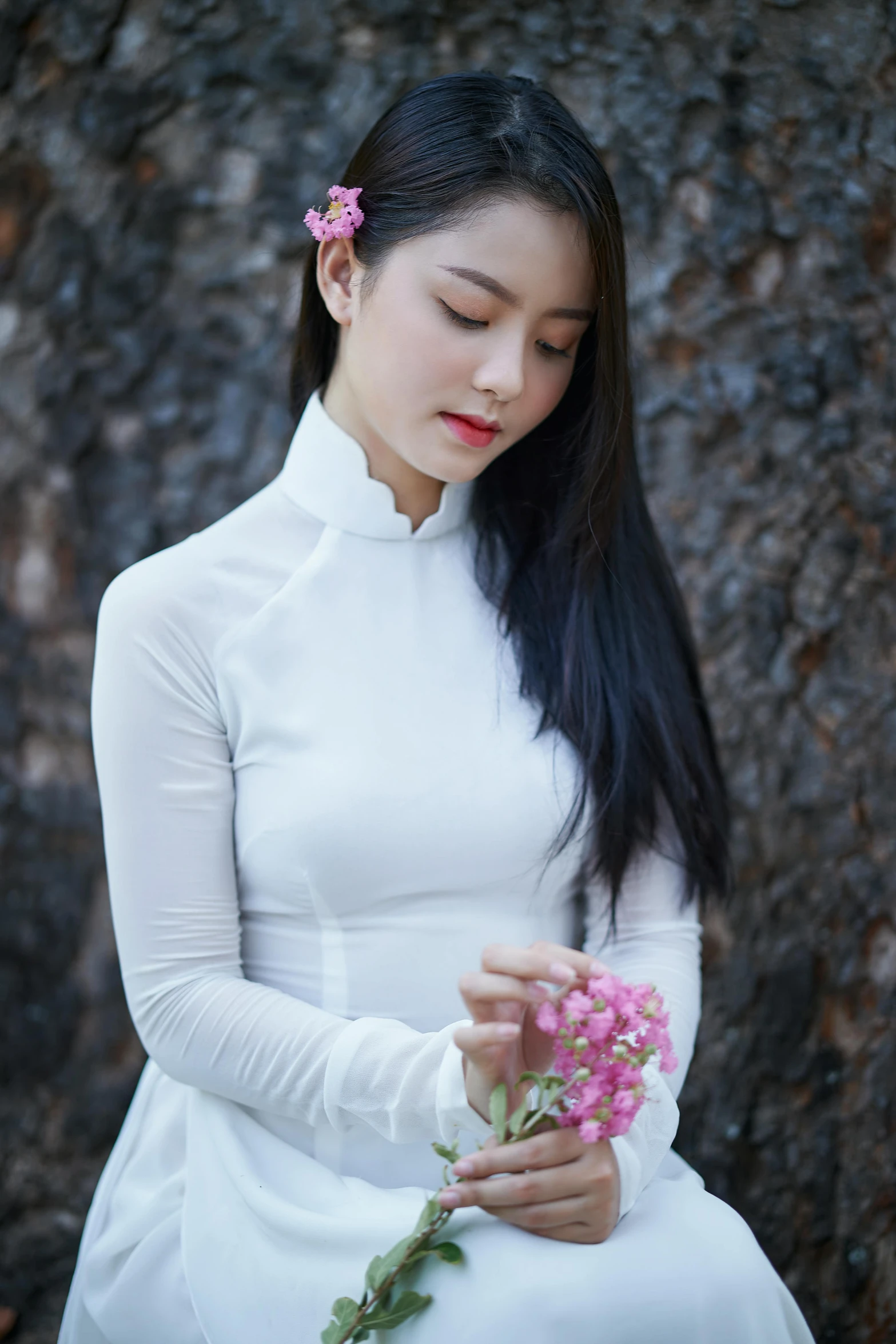 young lady in white dress sitting with flowers on hands