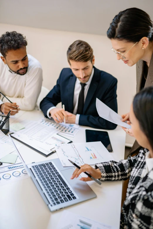 a group of people sitting around a table working on papers