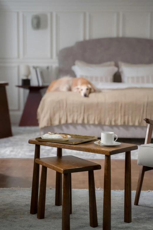 a dog is laying on top of the bed next to a table with two chairs