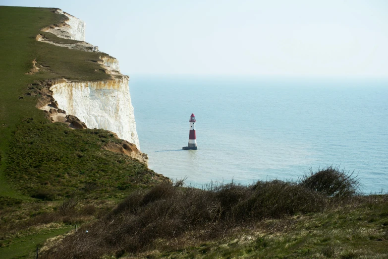 there is a lighthouse at the beach, with a small boat near the sea