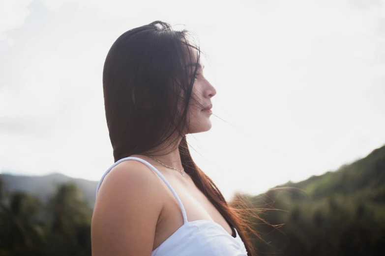 a woman in a white dress stands under a cloudy sky