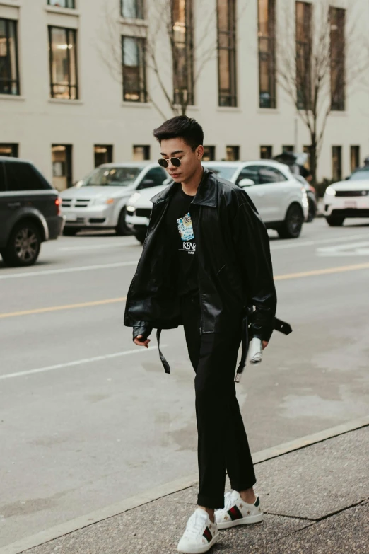 a man in a leather jacket walking down a street