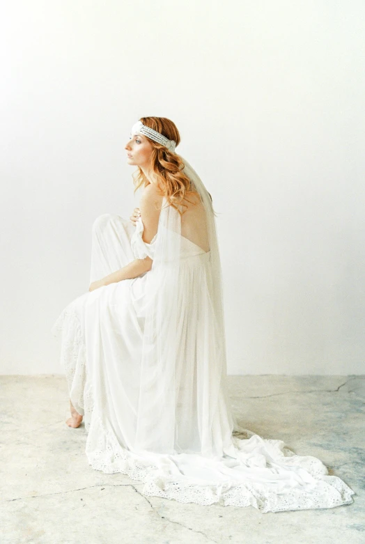 a woman in white dress posing with her back to the camera