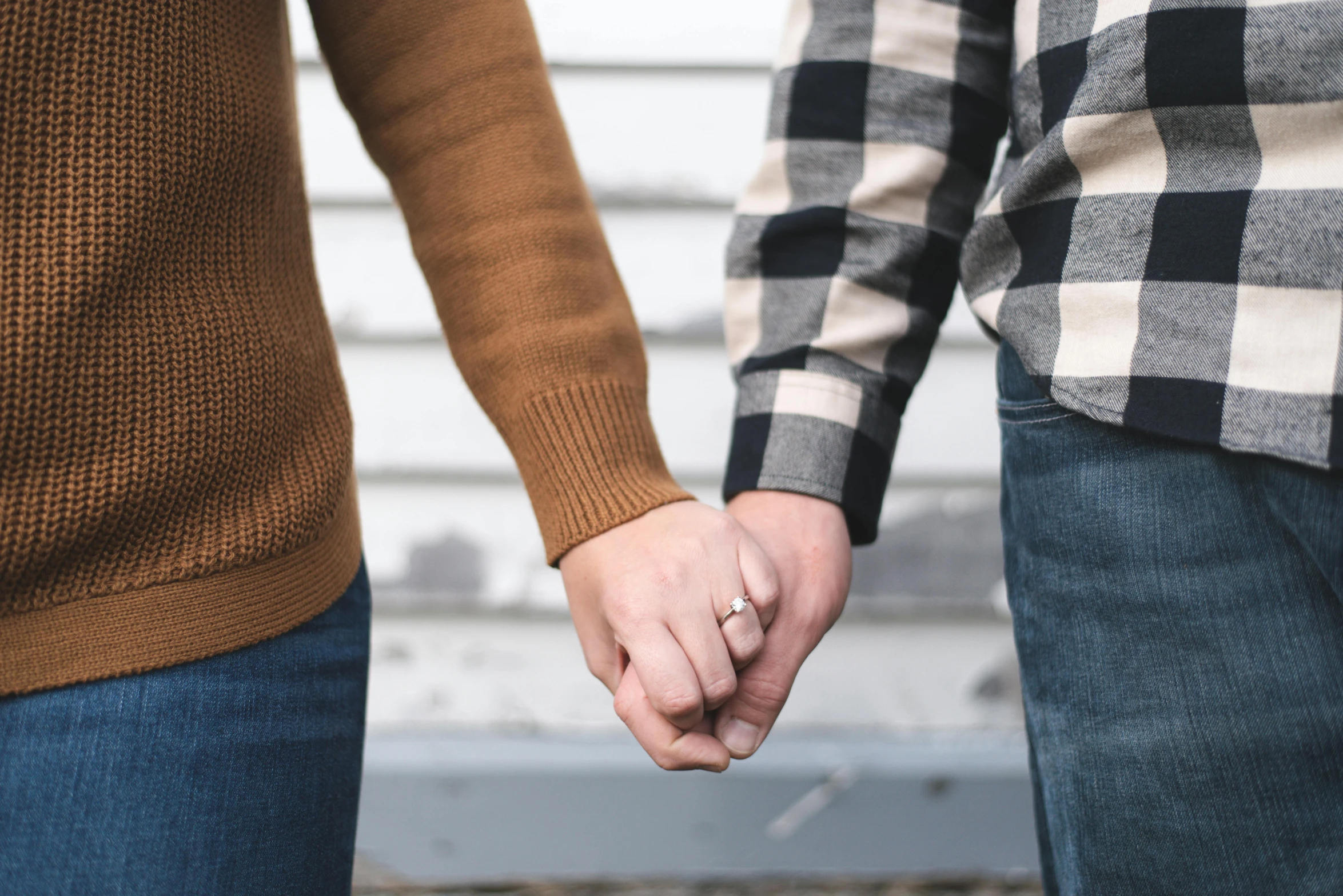 two people holding hands as they walk in front of a building