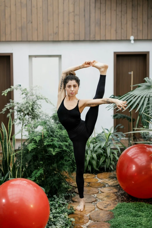 woman doing yoga outside in front of large red balls