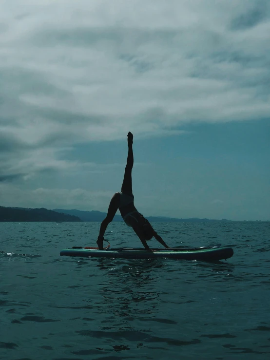 the person doing an arm stand on a surfboard in the ocean