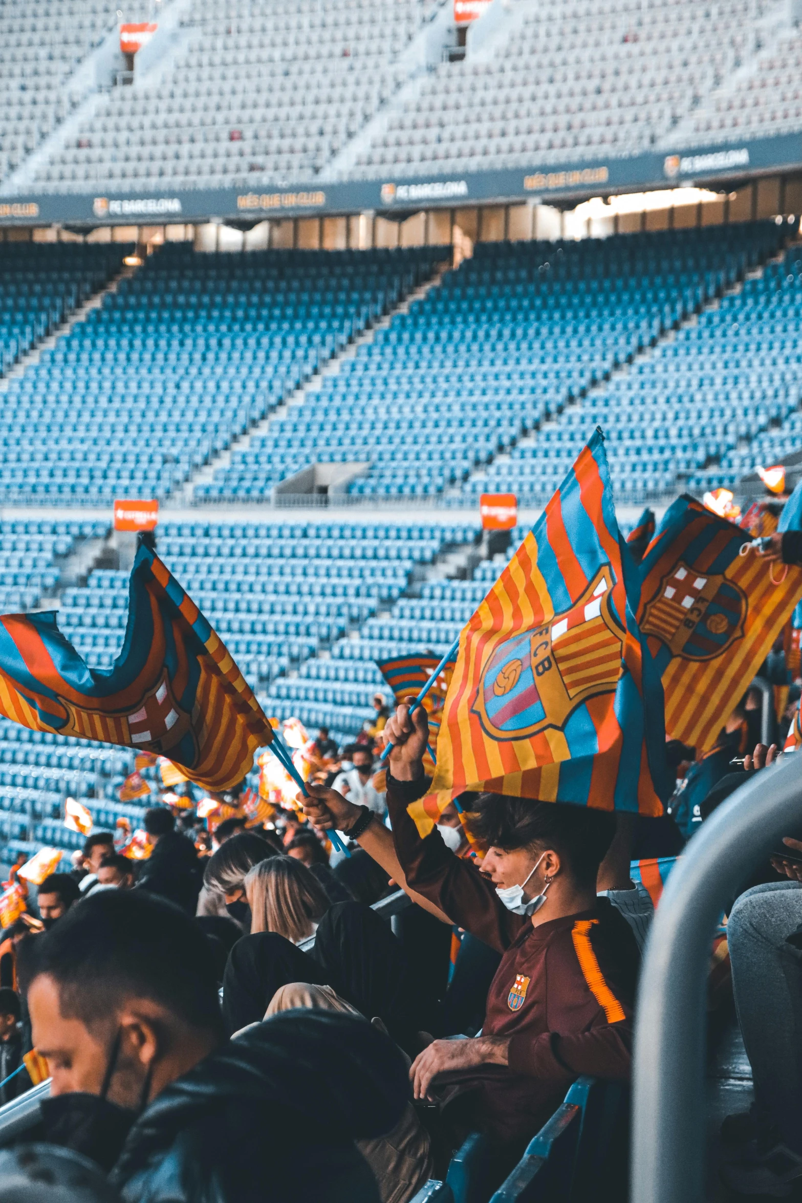 some people are sitting in a stadium and holding colorful flags