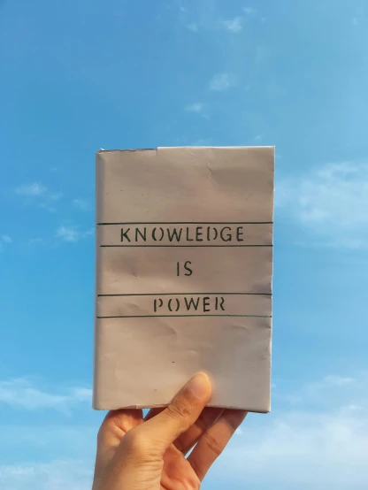 someone holding up a piece of paper that reads knowledge is power