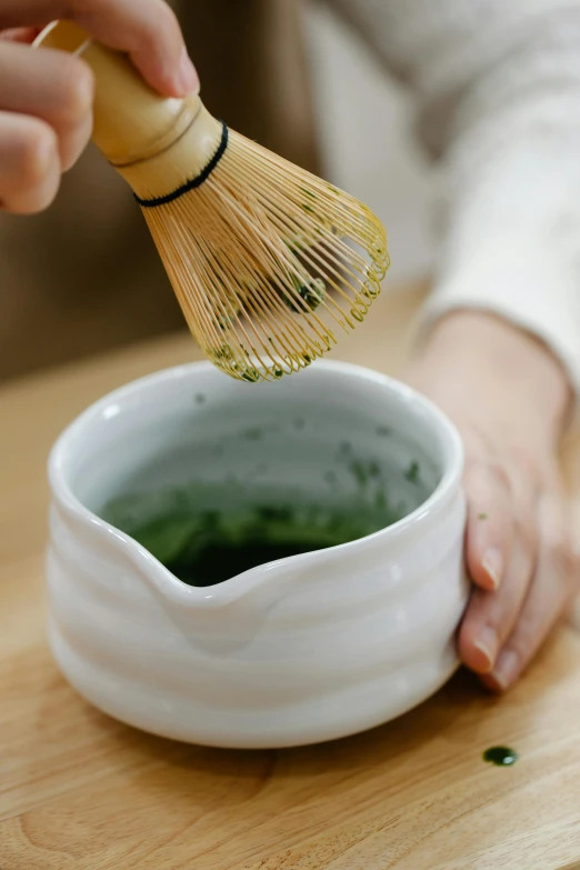 a woman holding a whisk that is in a small bowl