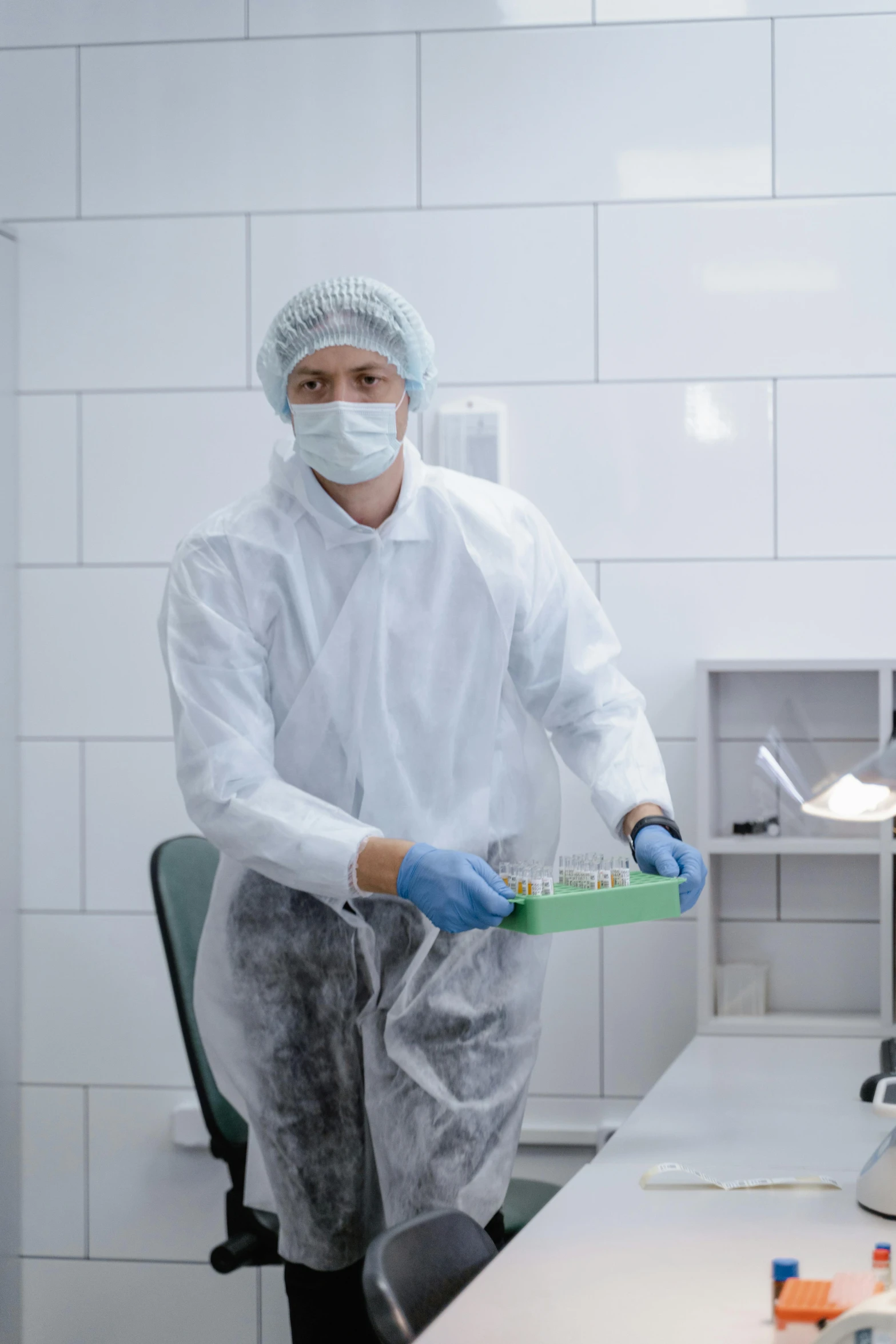 man wearing white lab coat and surgical mask while holding a toothpaste in a room
