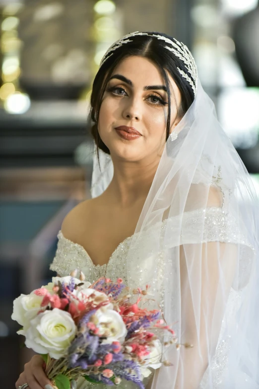 a bride is holding a bouquet while wearing her veil