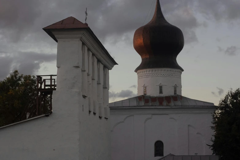 the tops of two white buildings with domes in cloudy weather