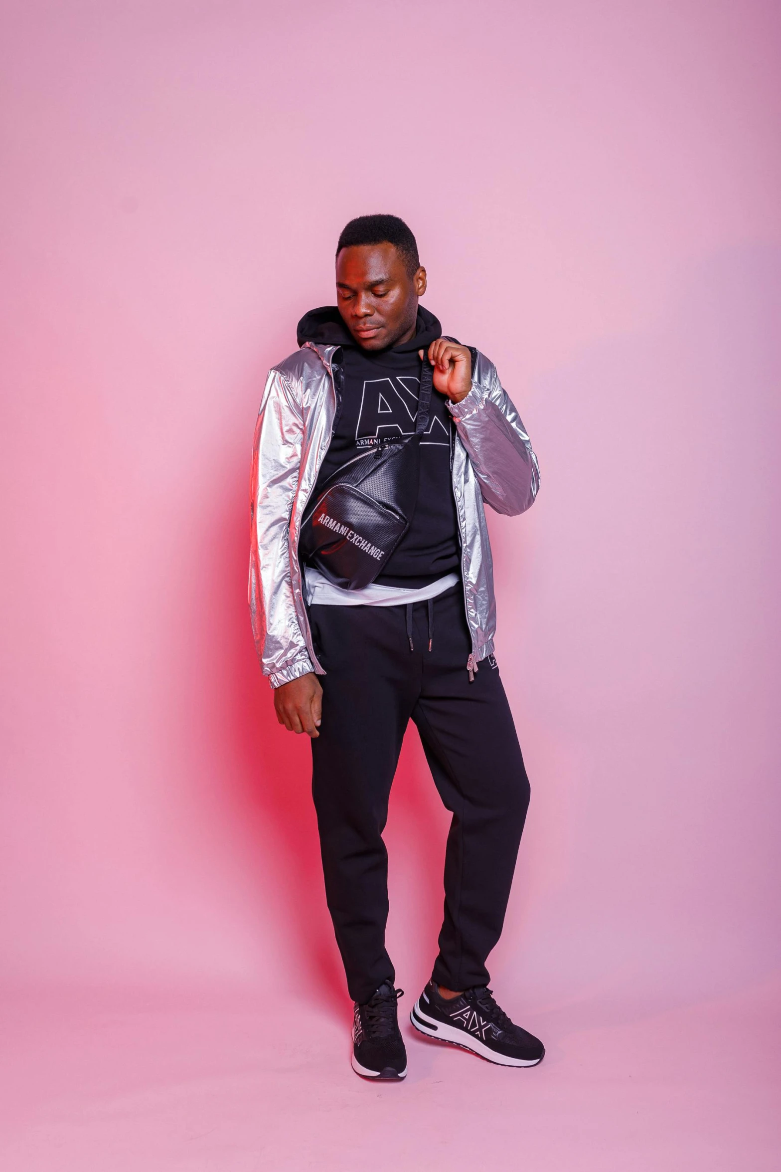 a black man in a pink background poses with his hand in the pocket