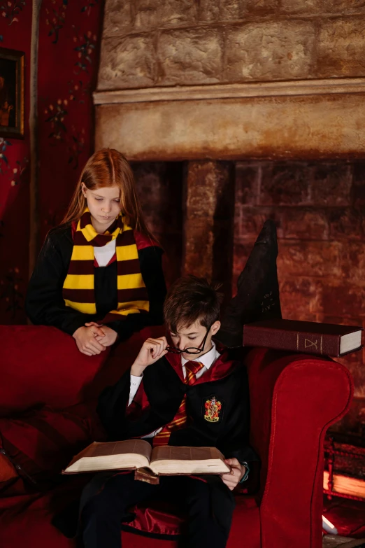 two children are reading books on a red couch