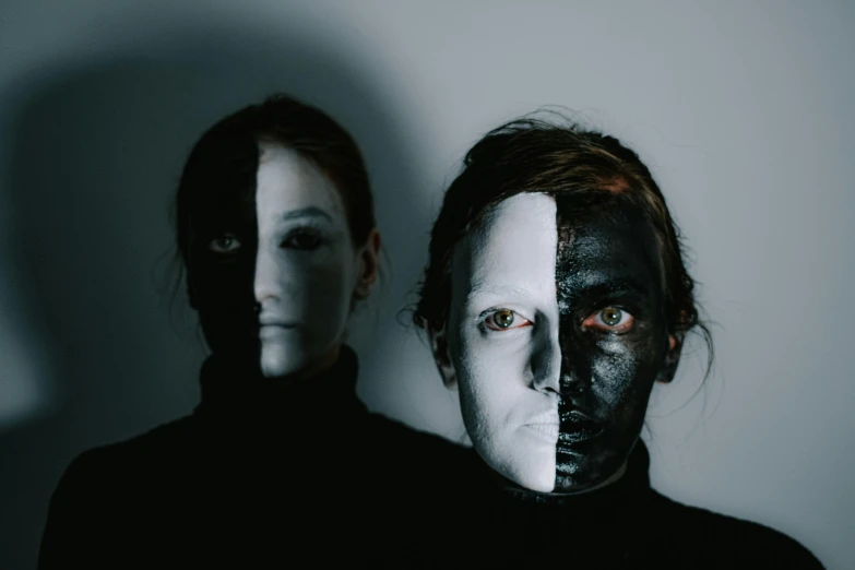 two different people, one with black and white face paint, the other wearing black