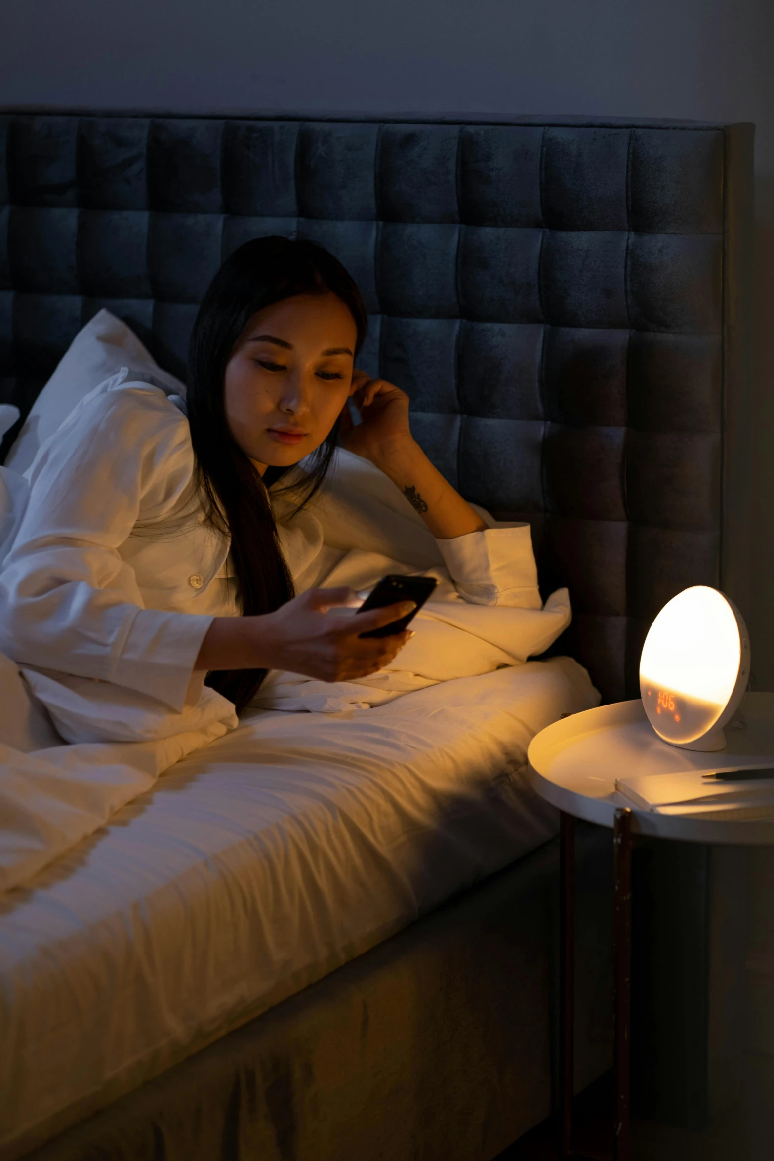 a woman is sitting in bed using a cell phone