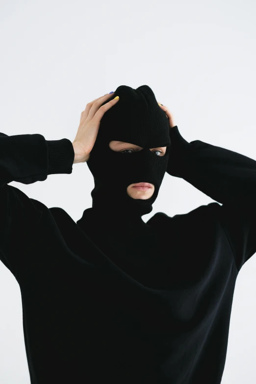 man in black with white background holding head with covering