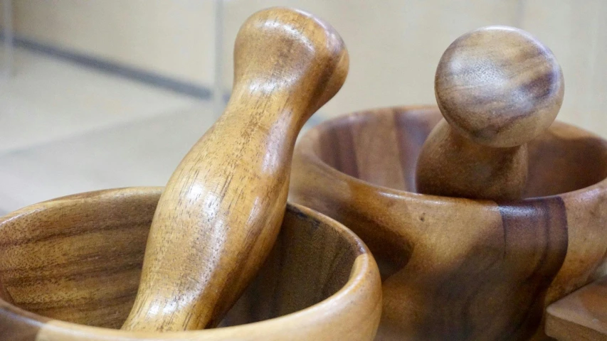 two wooden spoons, a knife and a bowl are stacked together