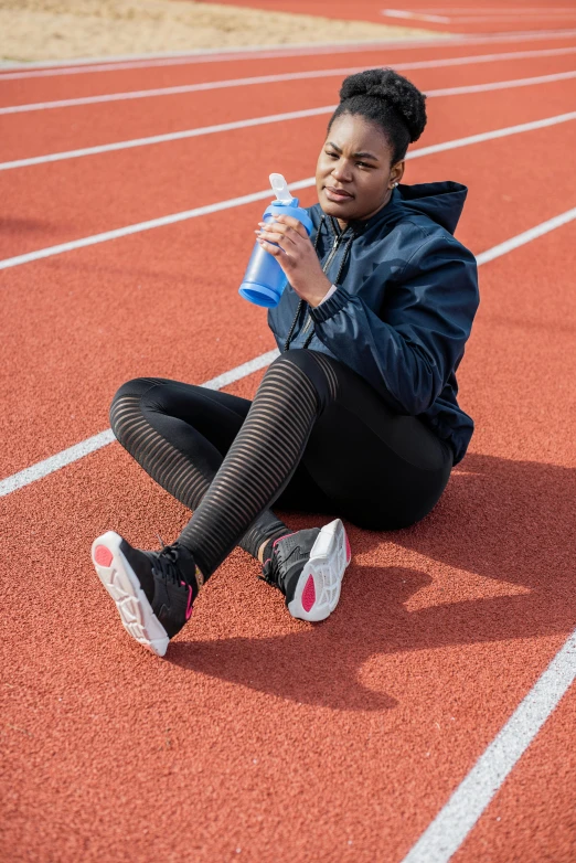 a woman with a water bottle kneeling on a track