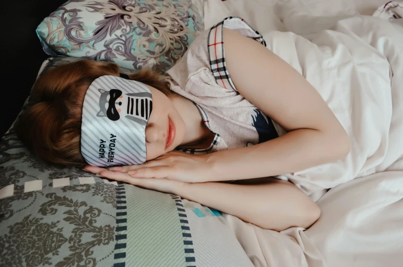 young child sleeping in bed with mask covering her eyes