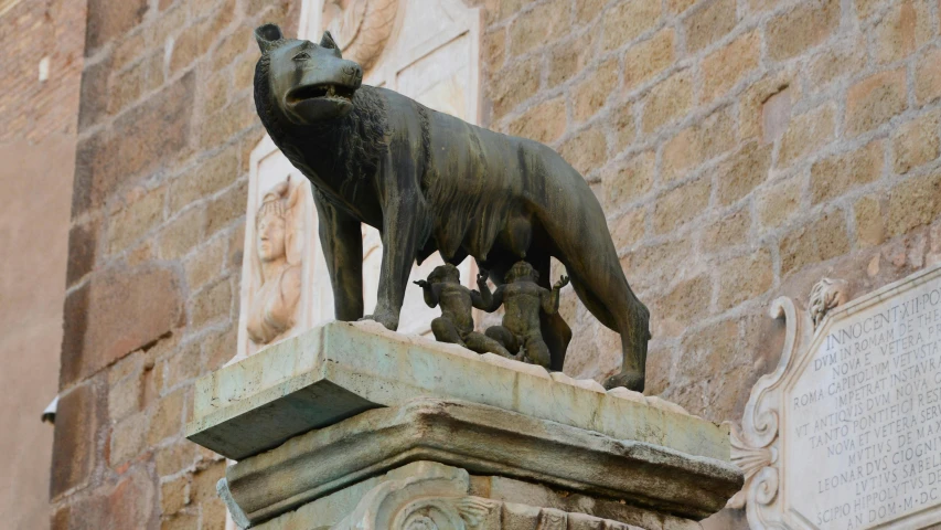 a statue of a wolf is in front of an old brick building
