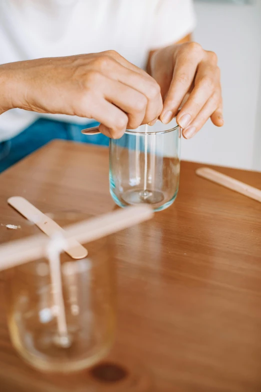 a person's hands on the table and pulling the top of the glass