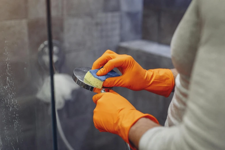 a person cleaning a glass with an orange glove