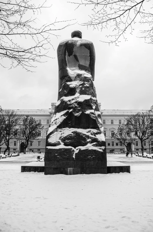 a monument with a man sitting on top of it in a snowy field